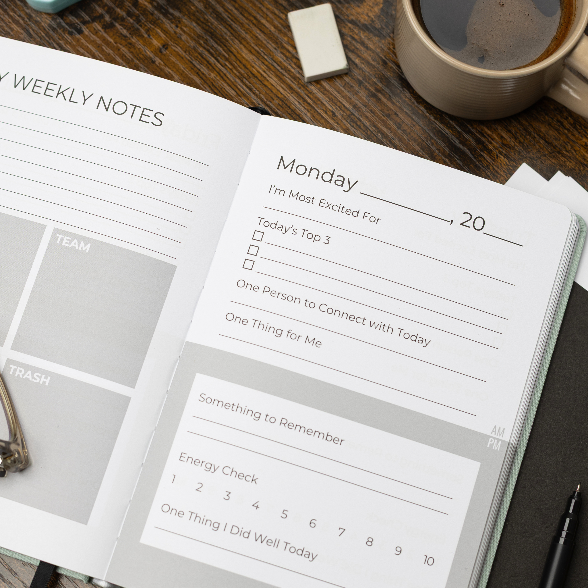 An open weekly TEACHERTIME teacher wellness journal planner page on a dark wooden desk, surrounded by a coffee cup, a small notepad, and pen.